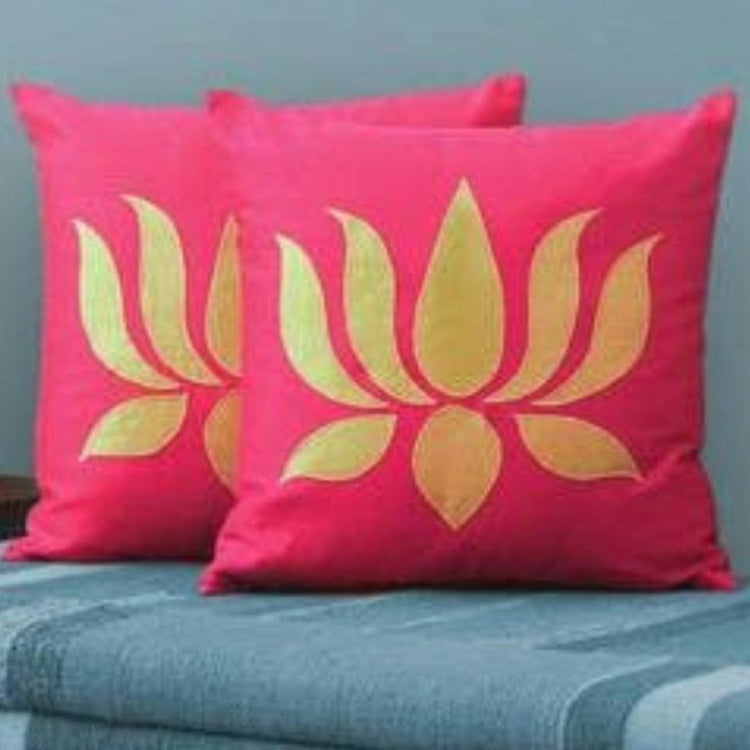 Two bright pink cushion covers with large gold coloured lotus flower silhouettes.