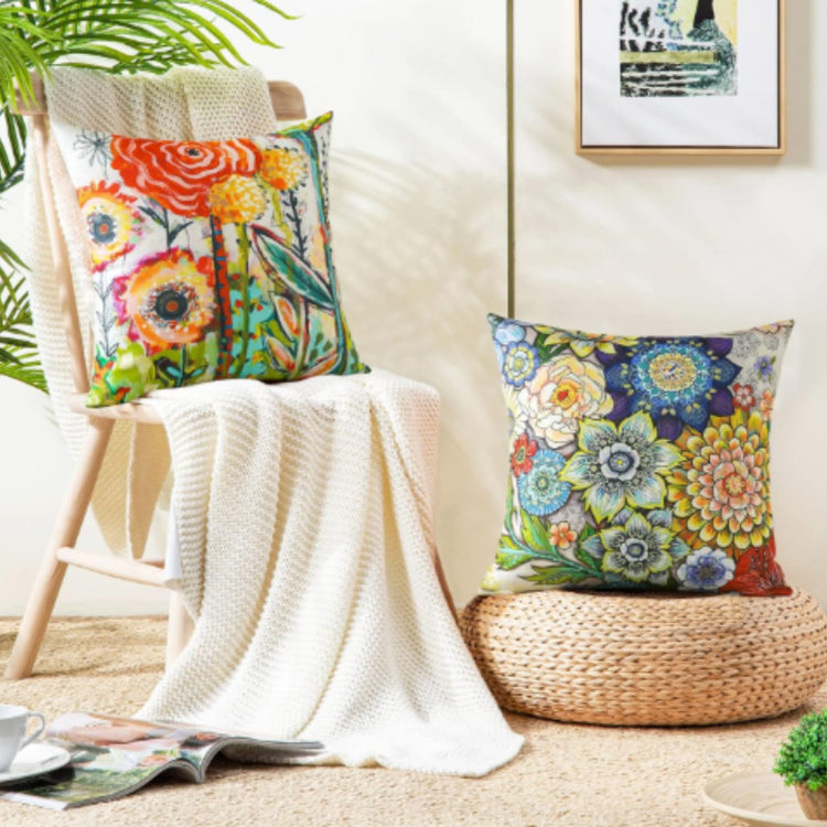 Colourful floral cushion covers displayed on a draped chair and a woven stool.