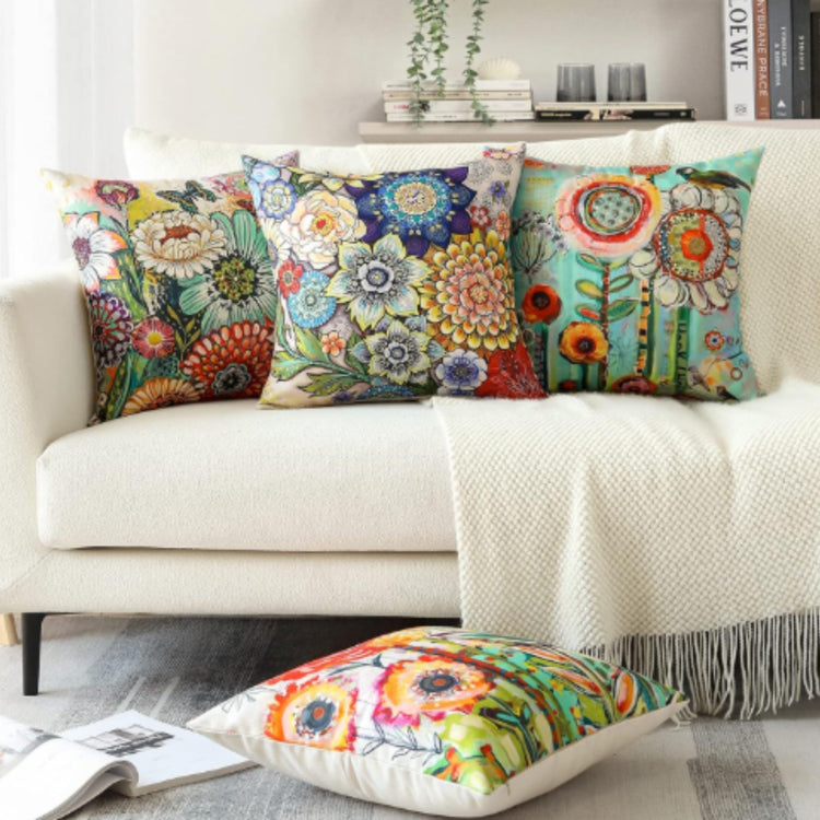 Colourful floral cushion covers arranged on a cream sofa and the floor.