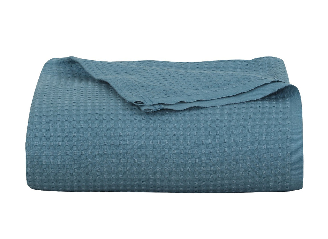 Folded teal textured blanket on a white background.