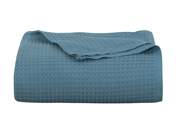 Folded teal textured blanket on a white background.