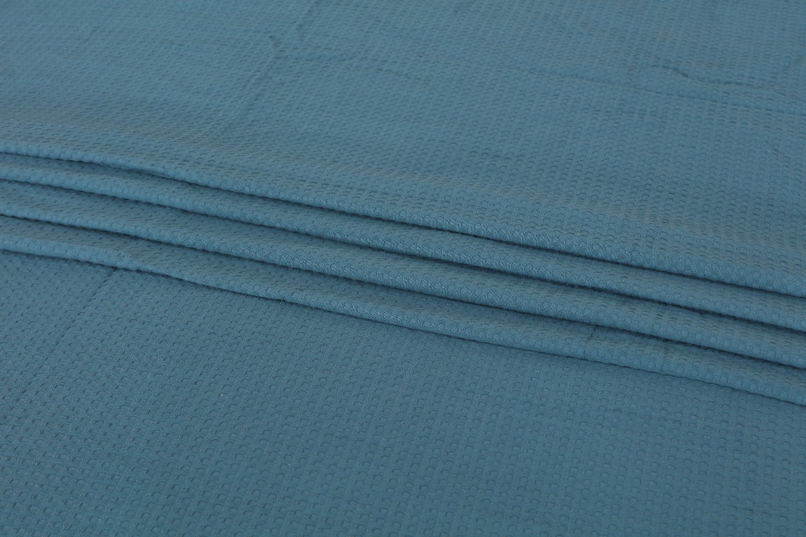 Close-up of teal blanket fabric and folded edges.