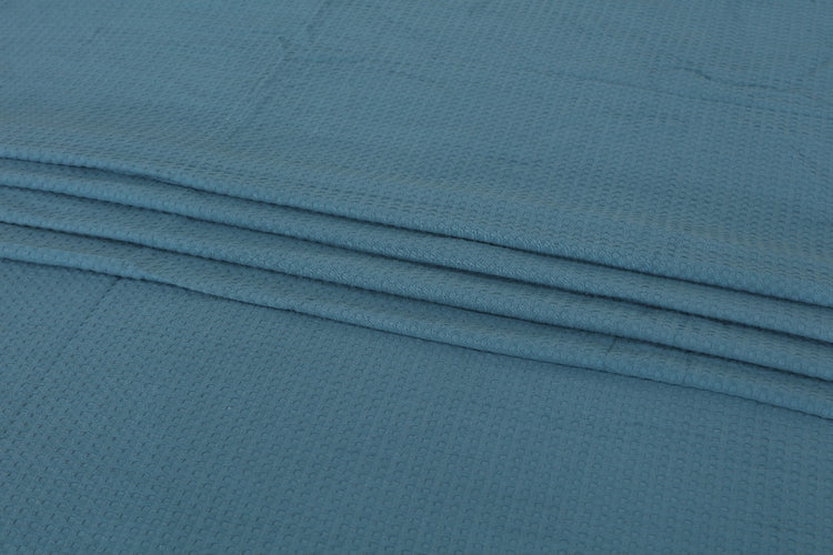 Close-up of teal blanket fabric and folded edges.