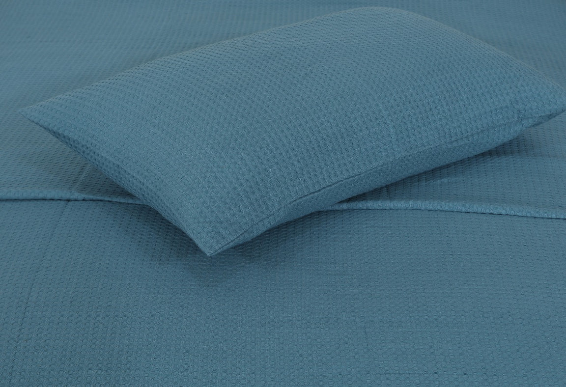 Close-up of a teal pillow cover against matching blanket fabric.