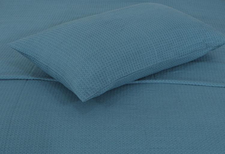 Close-up of a teal pillow cover against matching blanket fabric.