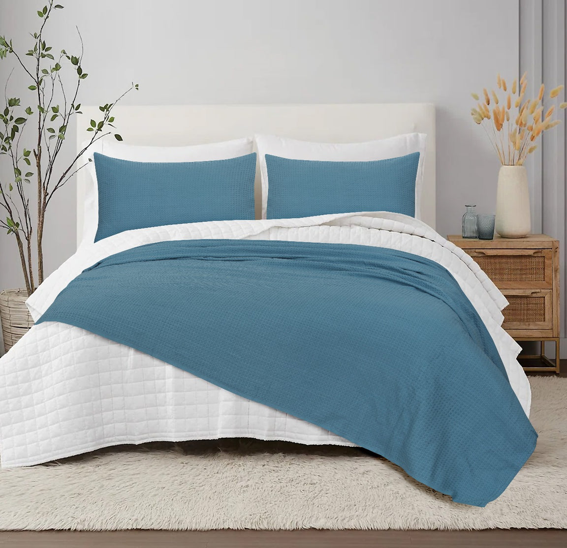 Teal textured blanket with matching pillow covers displayed on a bed.