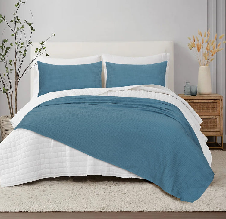 Teal textured blanket with matching pillow covers displayed on a bed.