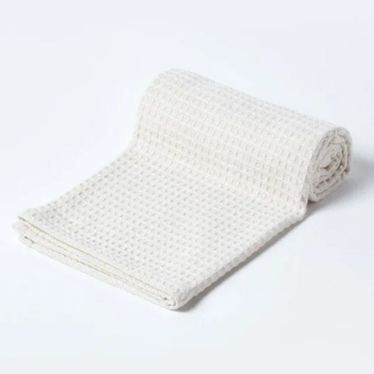 White waffle-textured blanket partly rolled on a white background