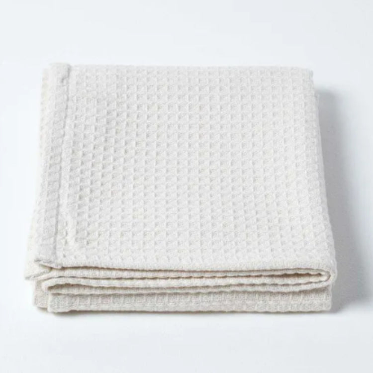 Folded white waffle-textured blanket on a white background