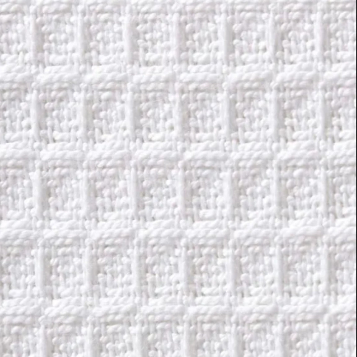 Close-up of a white blanket's raised waffle grid texture