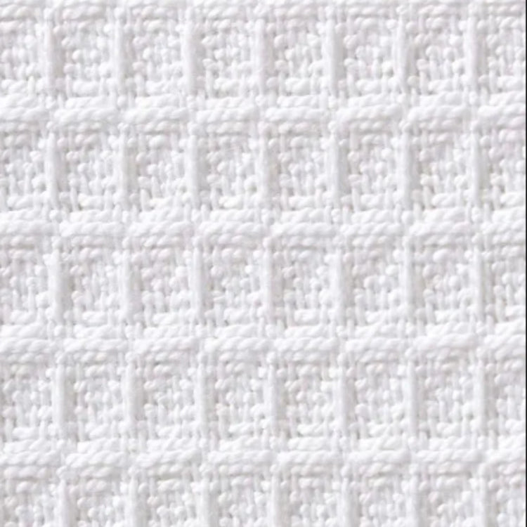 Close-up of a white blanket's raised waffle grid texture