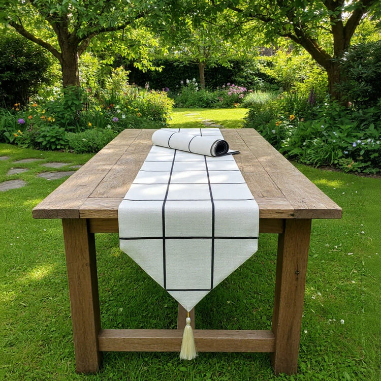 White table runner with a black grid pattern on an outdoor picnic table.