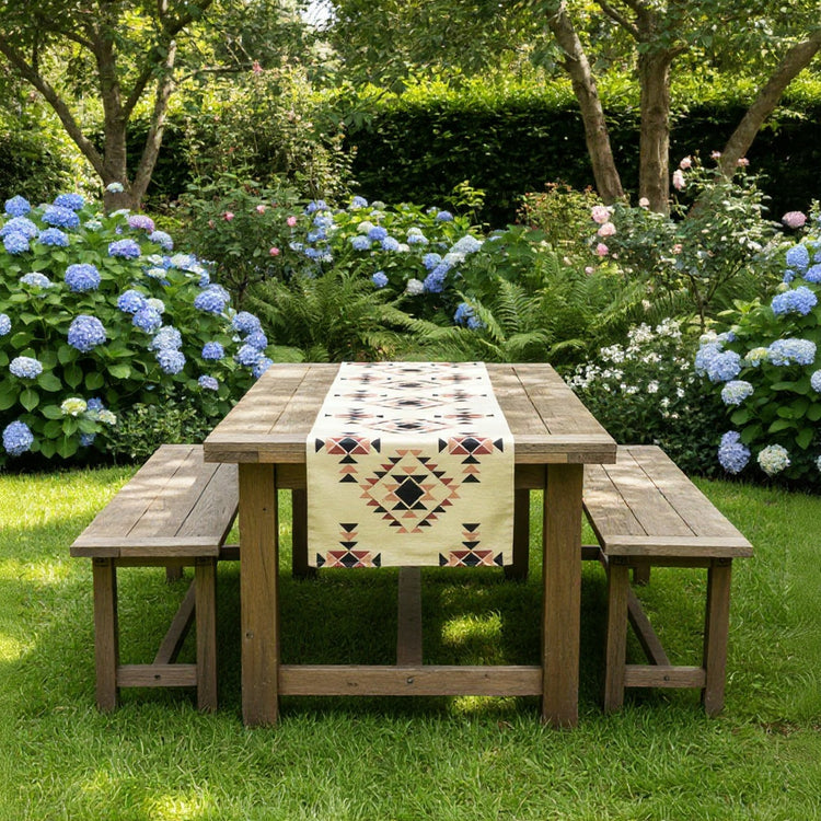 Cream geometric table runner on an outdoor wooden picnic table.