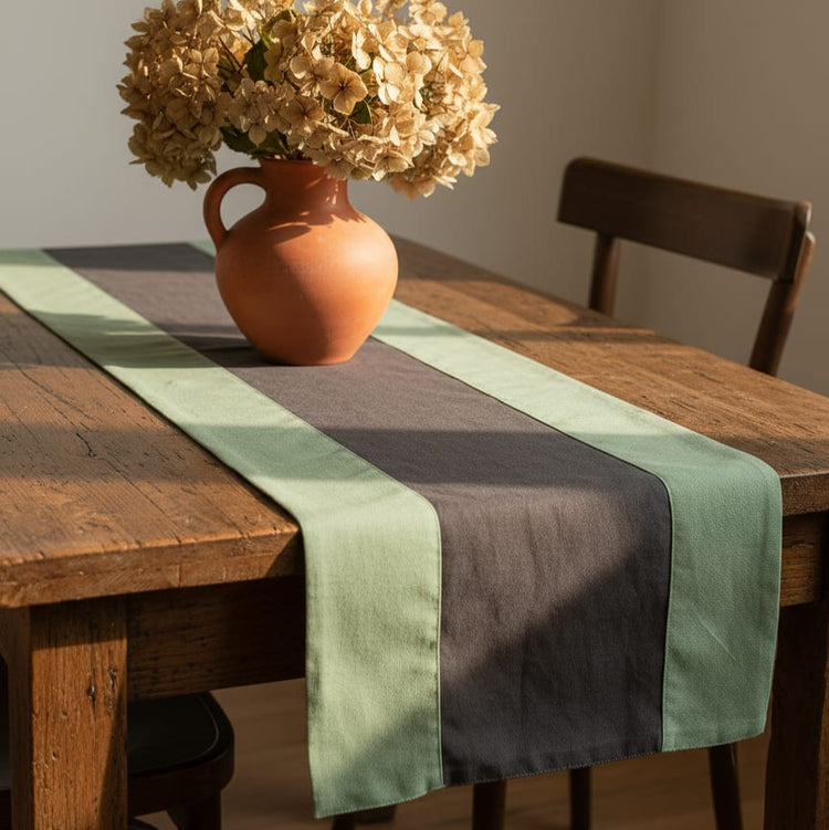 Sage green and dark grey colour-block table runner beneath a vase.
