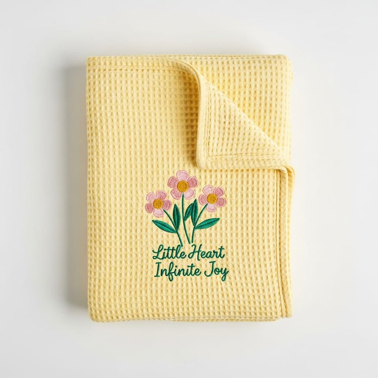 Yellow textured blanket with floral design and text on a light gray background