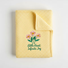 Yellow textured blanket with floral design and text on a light gray background
