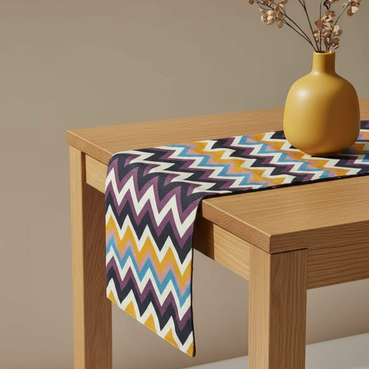 Multicoloured chevron table runner draped over a wooden table.