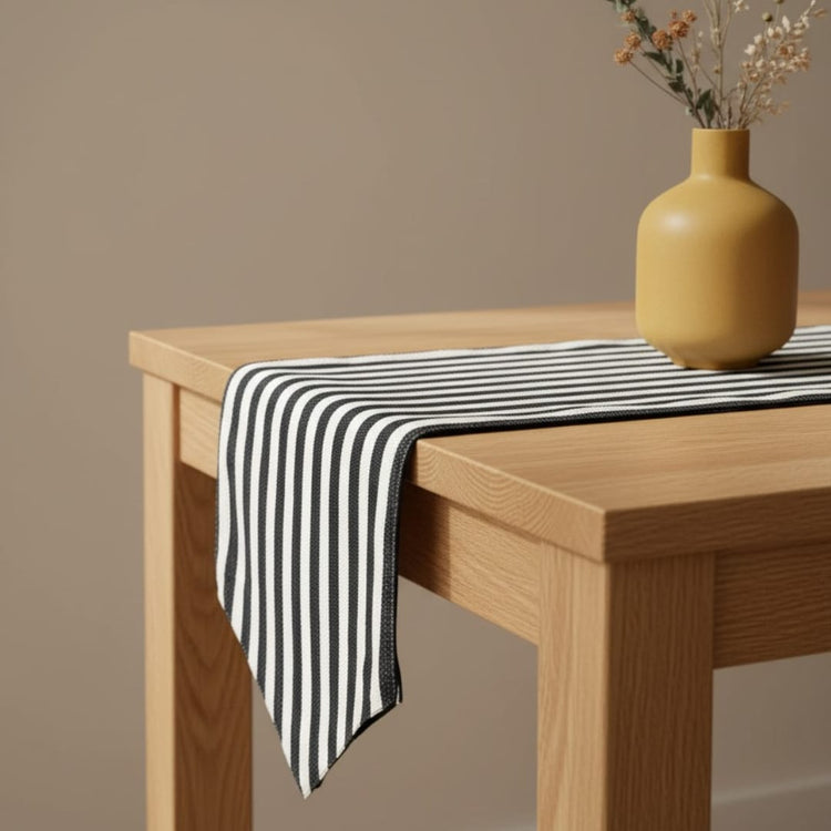 Black and white narrow-striped table runner draped over a wooden table.