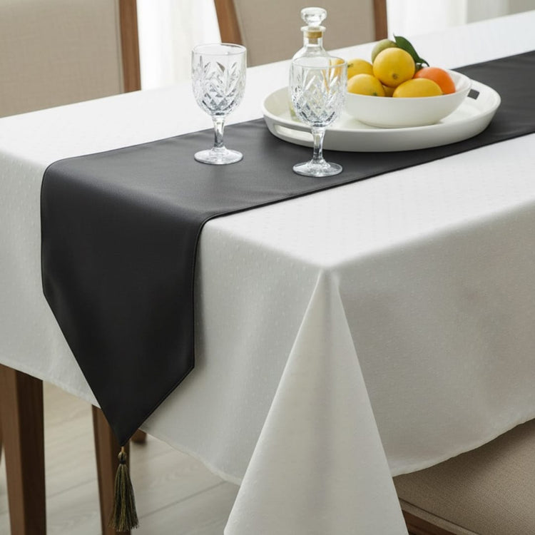 Close view of a black table runner over a white tablecloth.