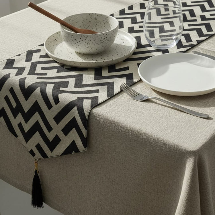 Black and cream angular geometric table runner beneath white tableware.