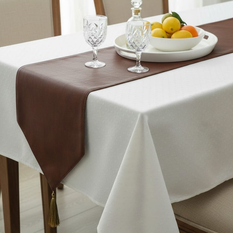 Close view of a brown table runner over a white tablecloth.