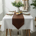 Plain brown pointed table runner over a white tablecloth.
