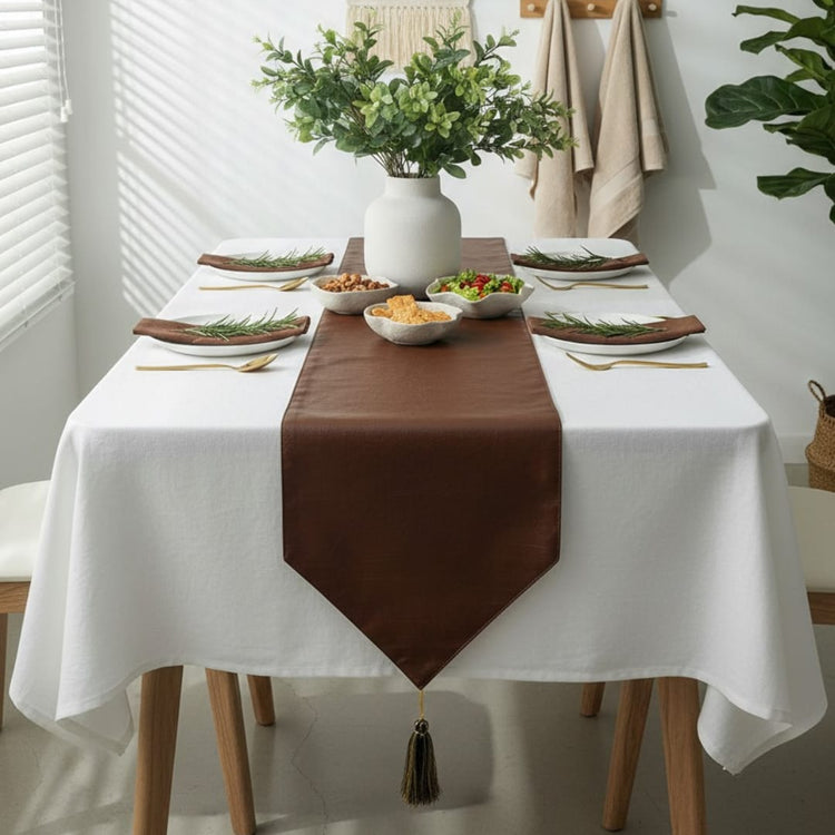 Plain brown pointed table runner over a white tablecloth.