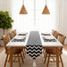 Black and white zigzag table runner with matching placemats on a dining table.