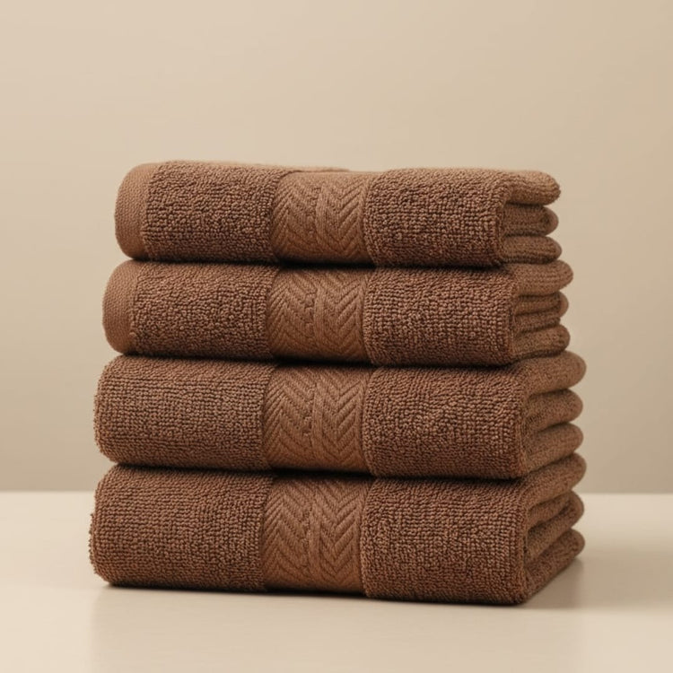 Four folded brown cotton hand towels stacked together.