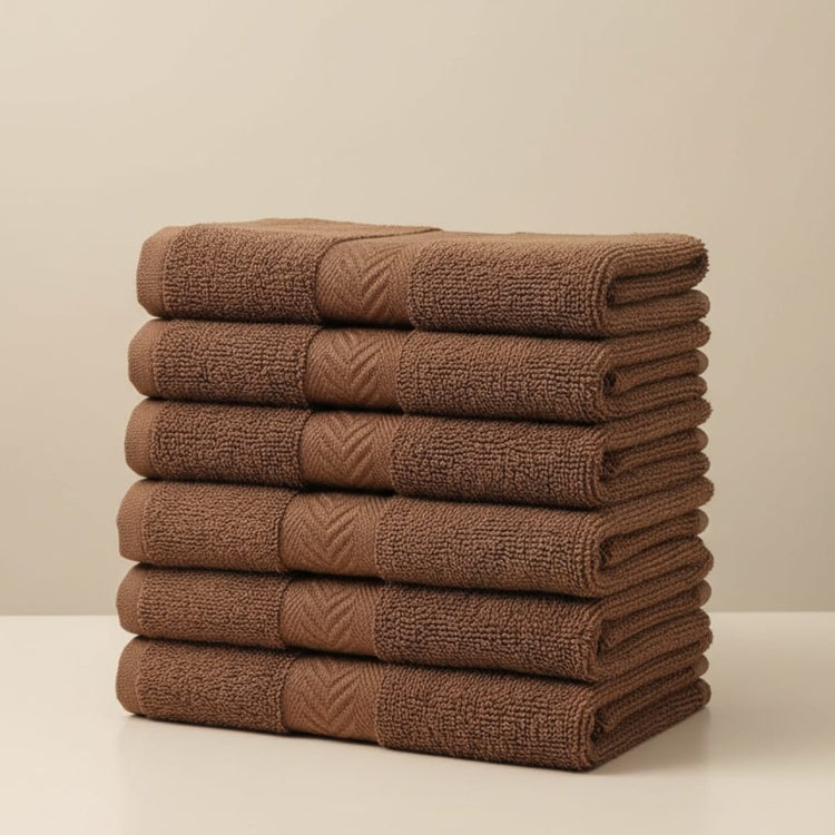 Stack of folded brown cotton hand towels with woven borders.