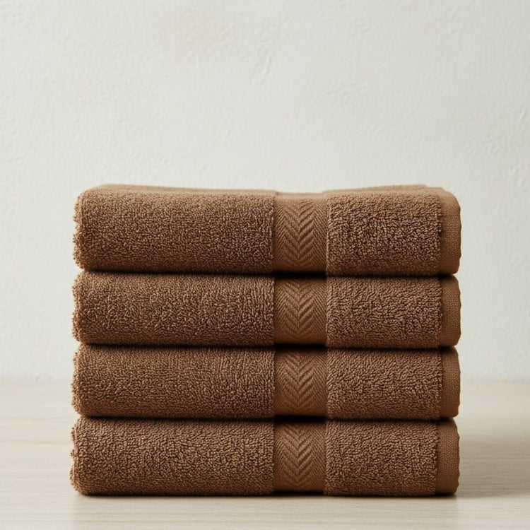 Four brown cotton hand towels in a neat horizontal stack.