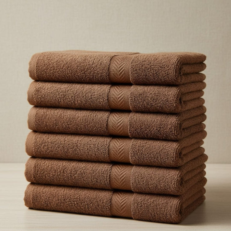 Tall stack of folded brown cotton hand towels.