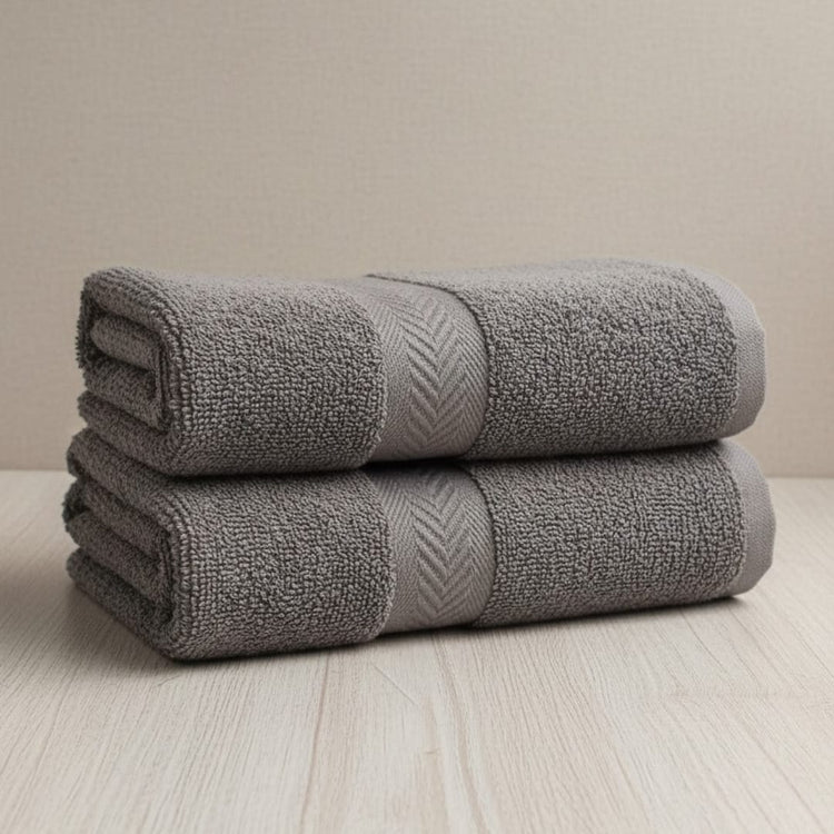 Two folded charcoal grey cotton hand towels.