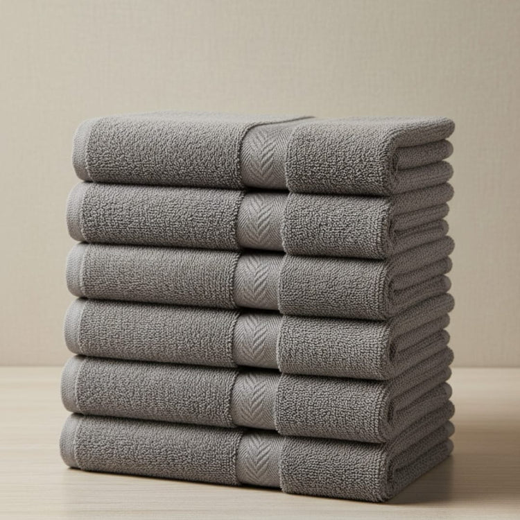 Tall stack of folded charcoal grey cotton hand towels.