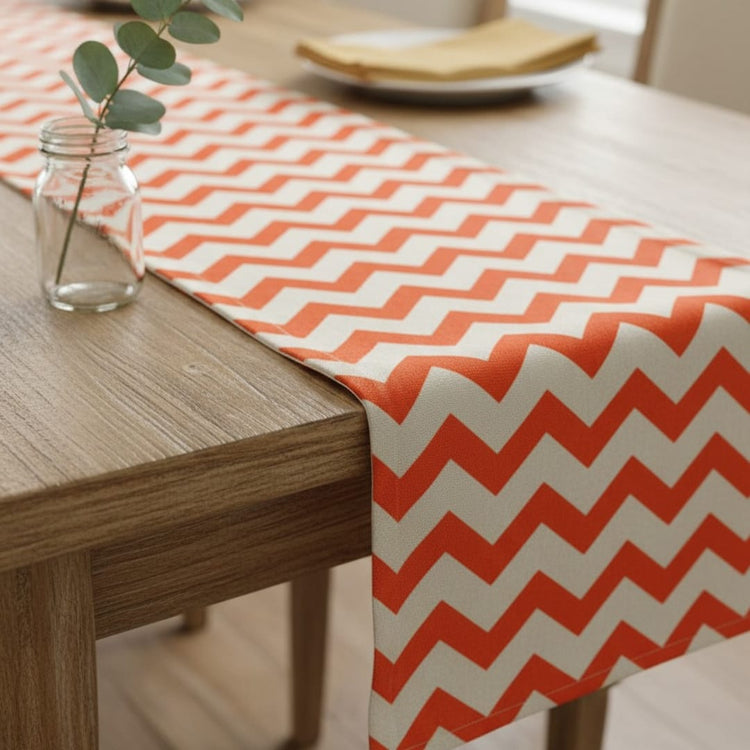 Orange and white chevron table runner on a wooden table.