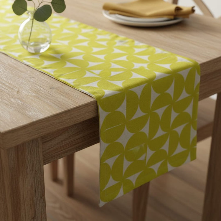 Lime green and white geometric petal-pattern table runner on a wooden table.