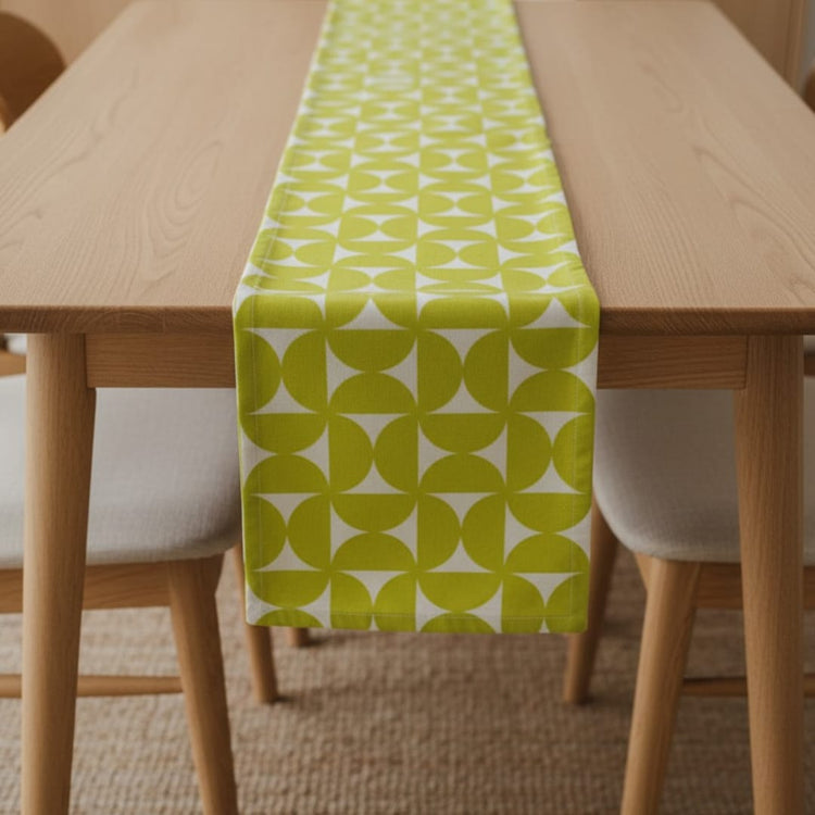 Lime green and white geometric petal-pattern table runner on a wooden table.