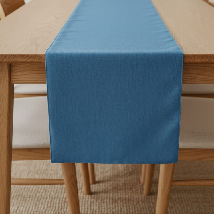 Plain blue table runner on a wooden dining table.