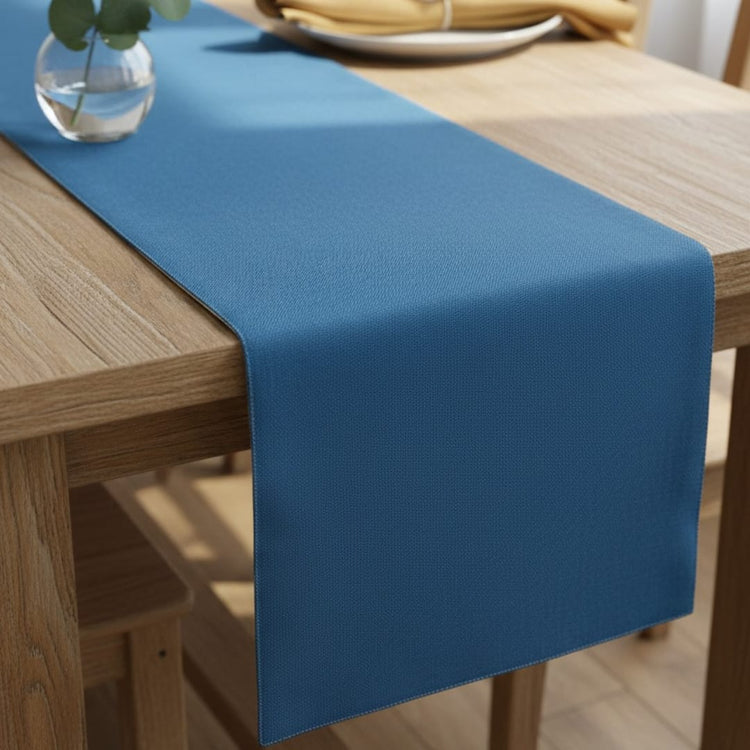Plain blue table runner on a wooden dining table.