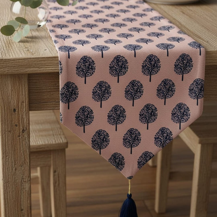 Dusty pink table runner with navy tree motifs and a tasselled end.