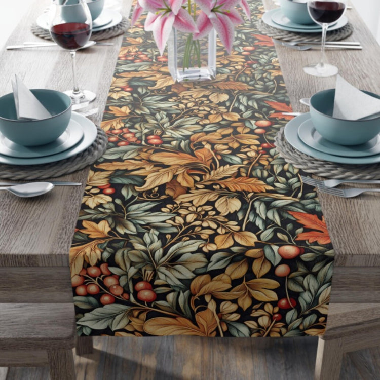 Dark table runner with dense gold, green and orange botanical motifs on a dining table.