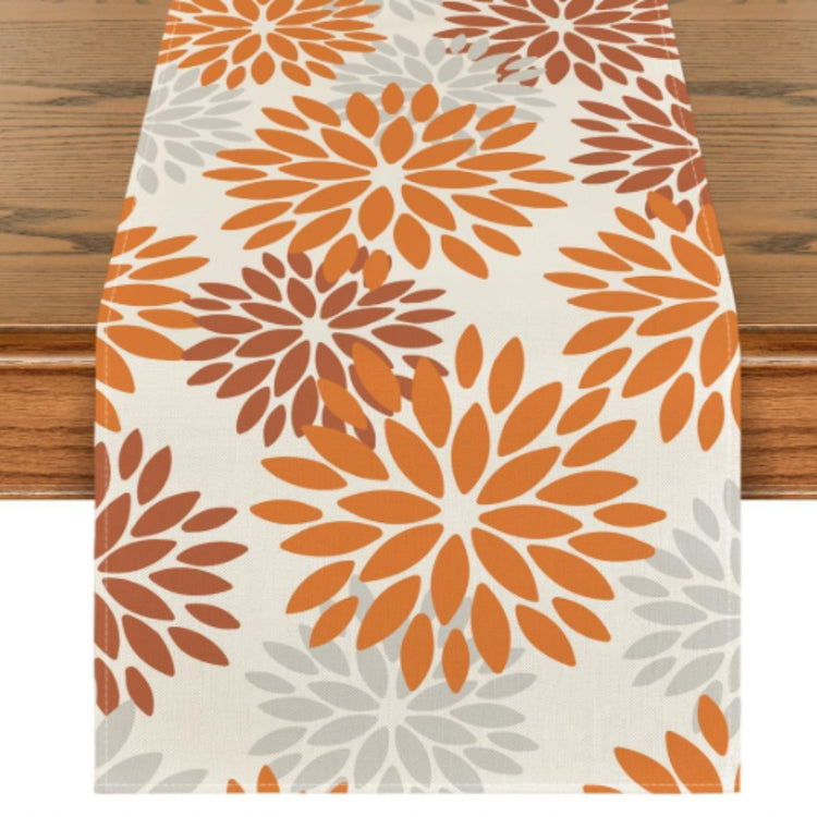 Cream table runner with orange floral motifs.