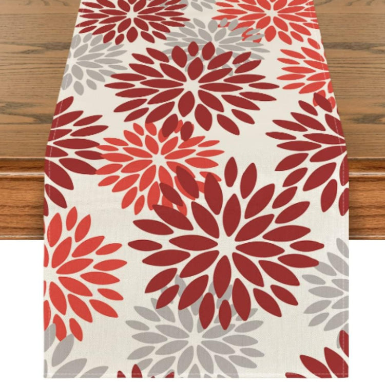 Cream table runner with red and grey floral motifs.