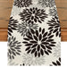 Cream table runner with black and grey large floral motifs.