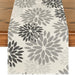 Cream table runner with light and dark grey floral motifs.