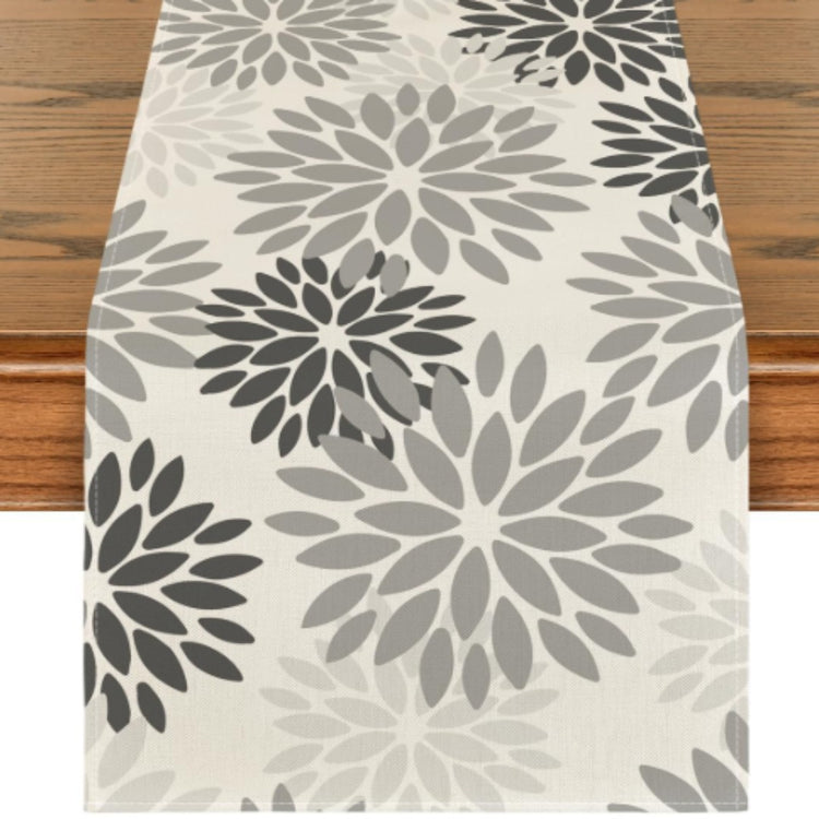Cream table runner with light and dark grey floral motifs.