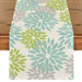 Cream table runner with turquoise and lime green floral motifs.