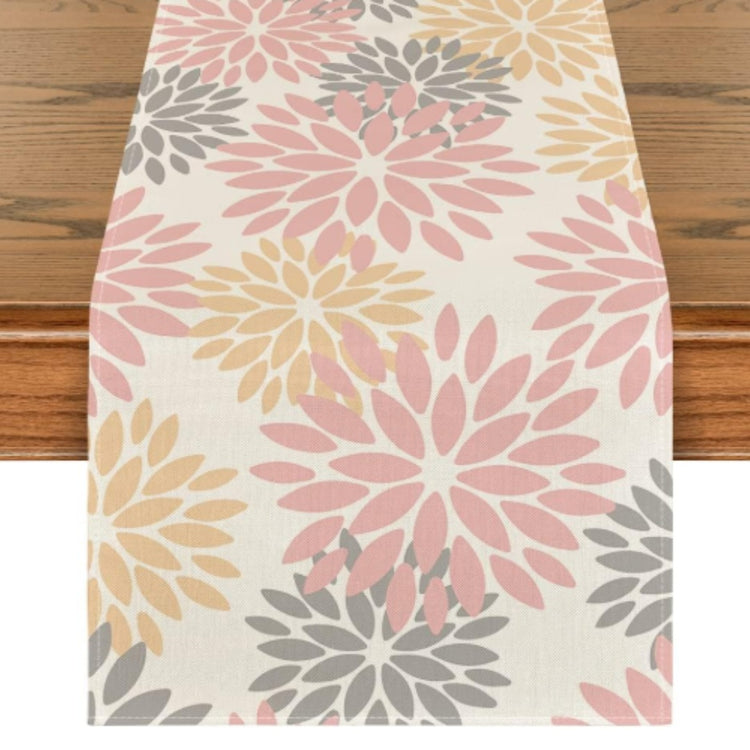 Cream table runner with pink, grey and beige floral motifs.