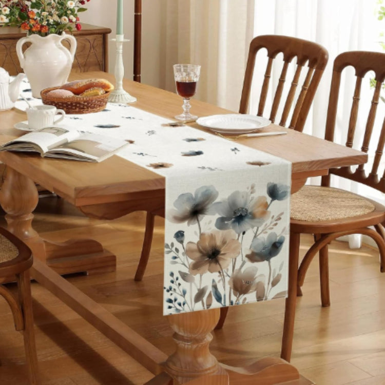 Cream table runner with large muted blue and beige watercolour-style flowers.