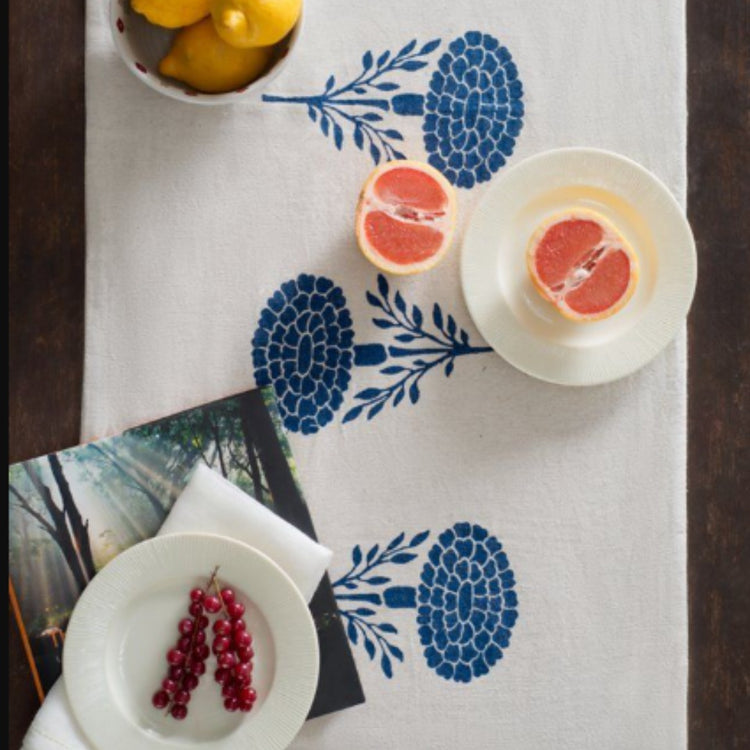 White table runner with blue stylised floral motifs beneath tableware.